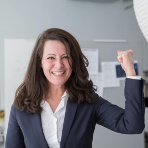 Smiling businesswoman in a smart suit celebrating a success in the office.